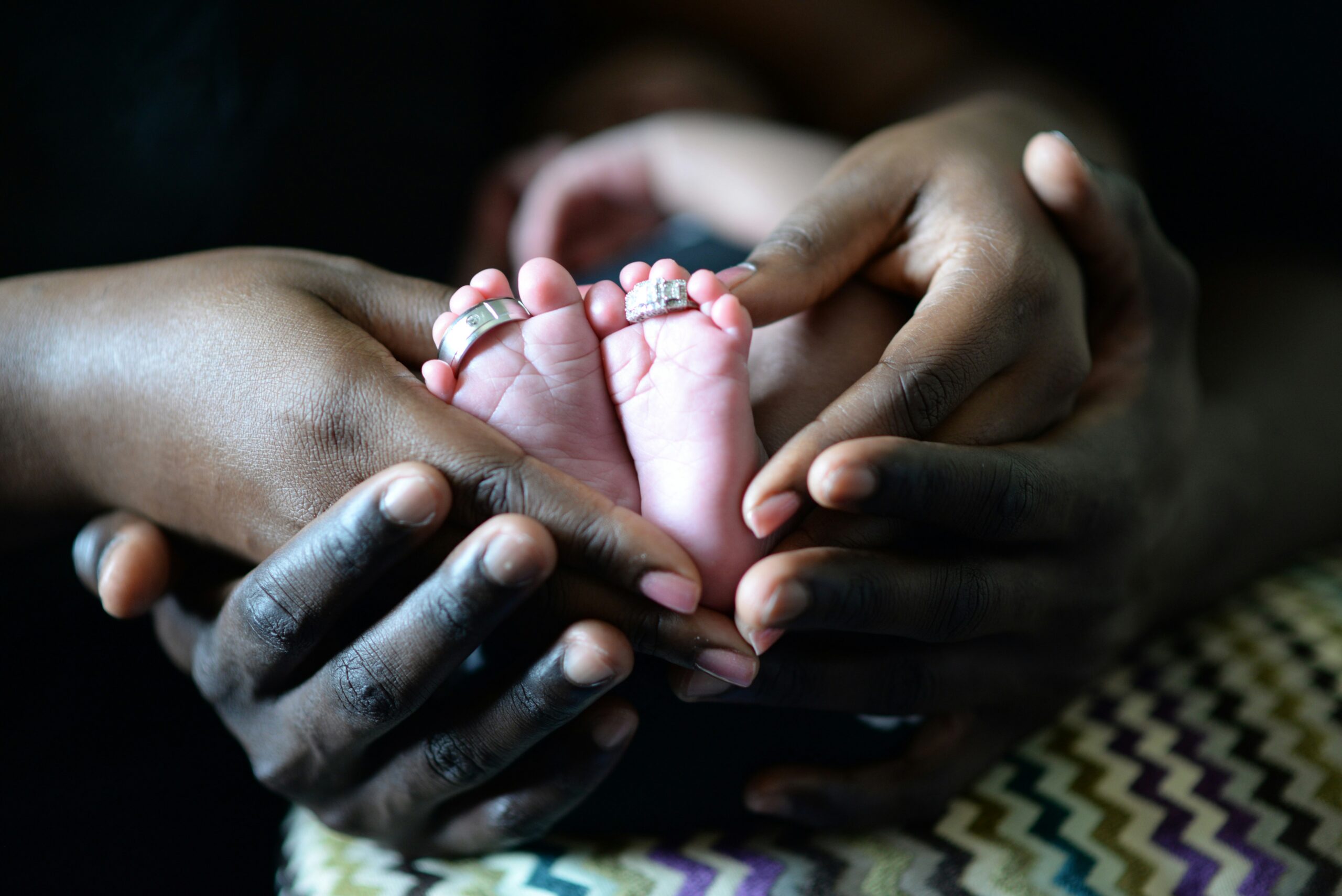 A mother holding the legs of her new born baby
